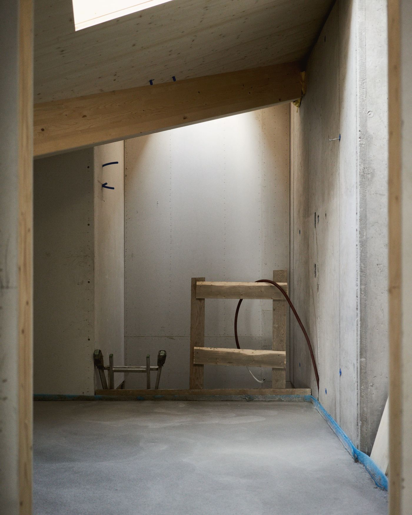 Chantier de rénovation : structure en bois et béton sous une verrière, avant les finitions